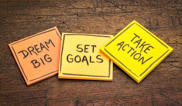 dream big, set goals, take action - motivational advice or reminder on colorful sticky notes against rustic wood
