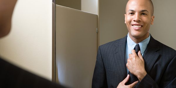 Man adjusting tie in mirror Man adjusting tie in mirror